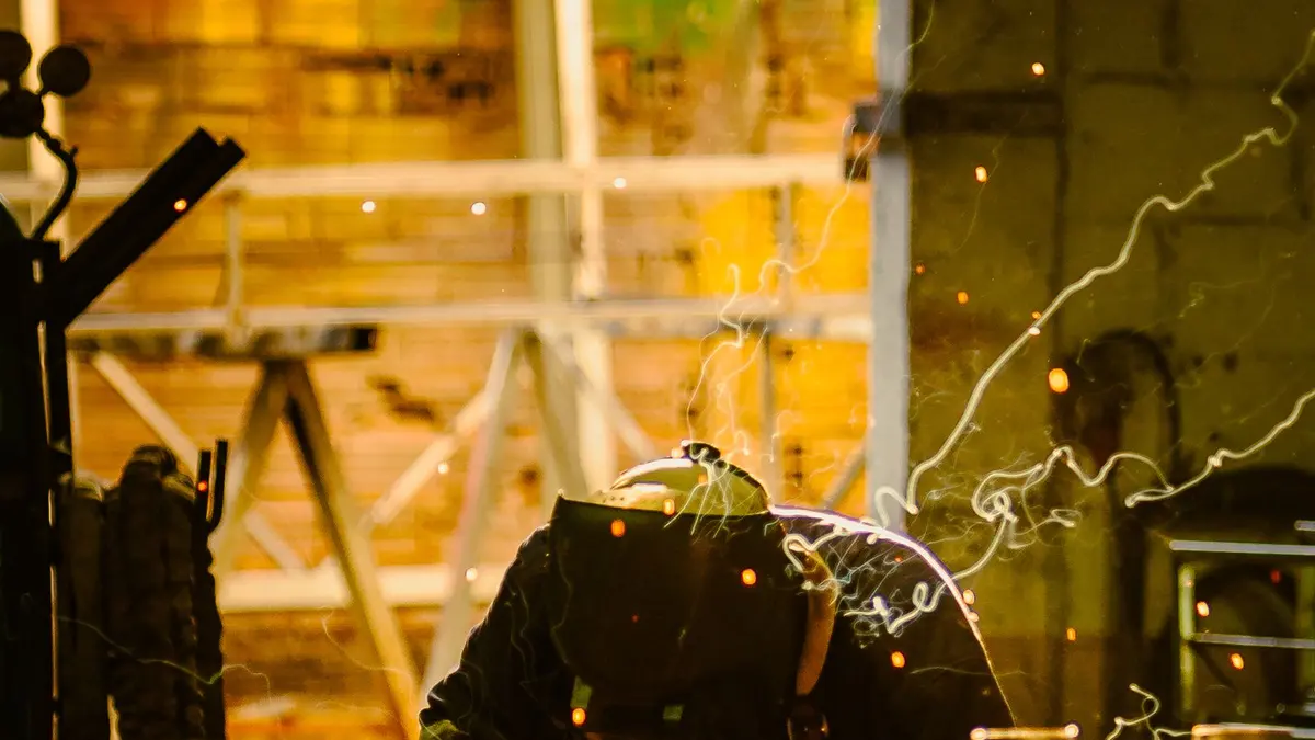 Metalworker wearing a welding helmet and protective clothing in a workshop