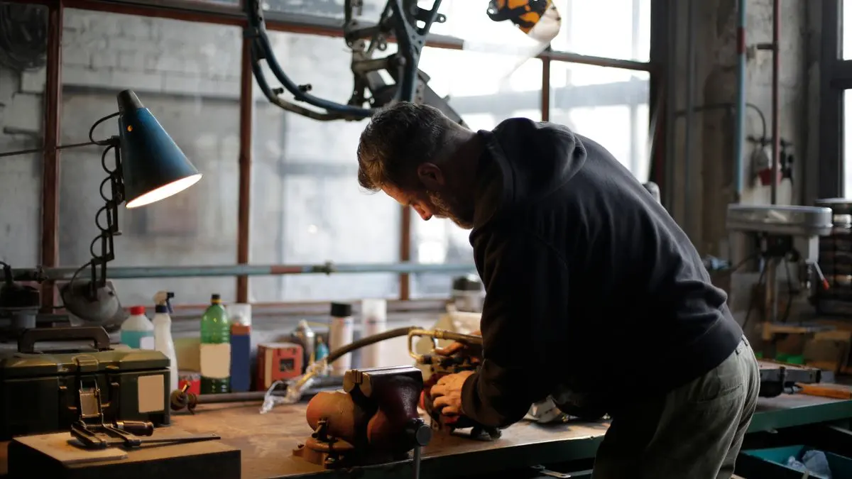 Technician repairing a metal component at a workshop bench