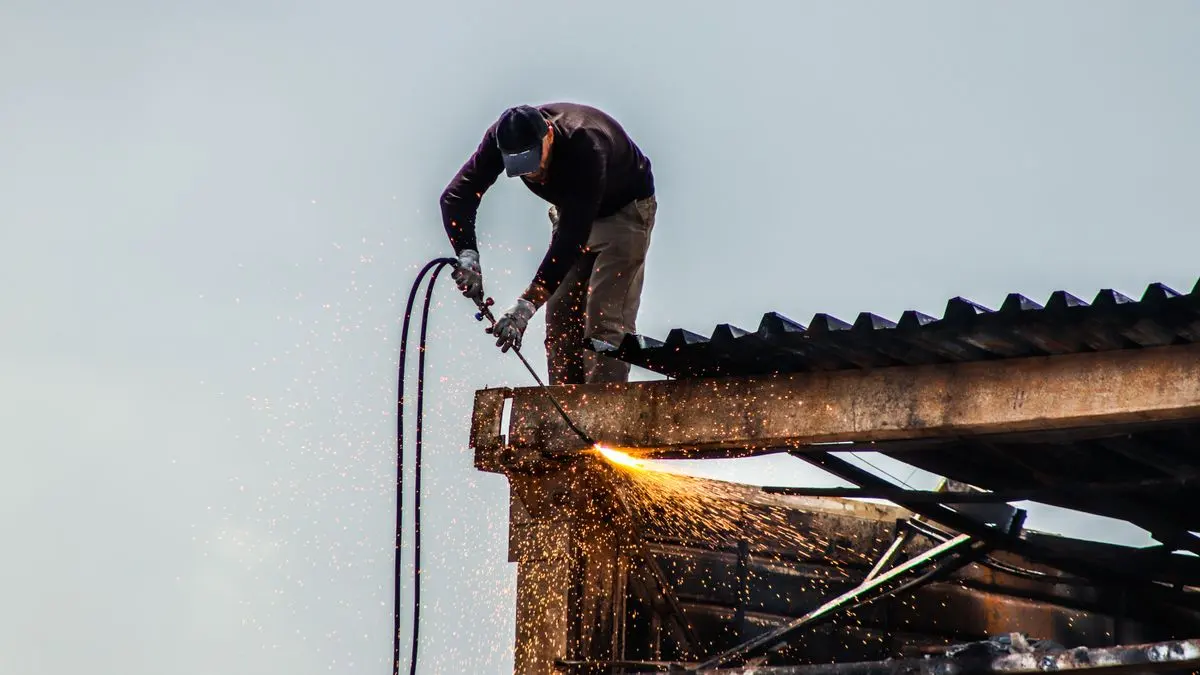 Worker carrying out metal roofing fabrication on a building