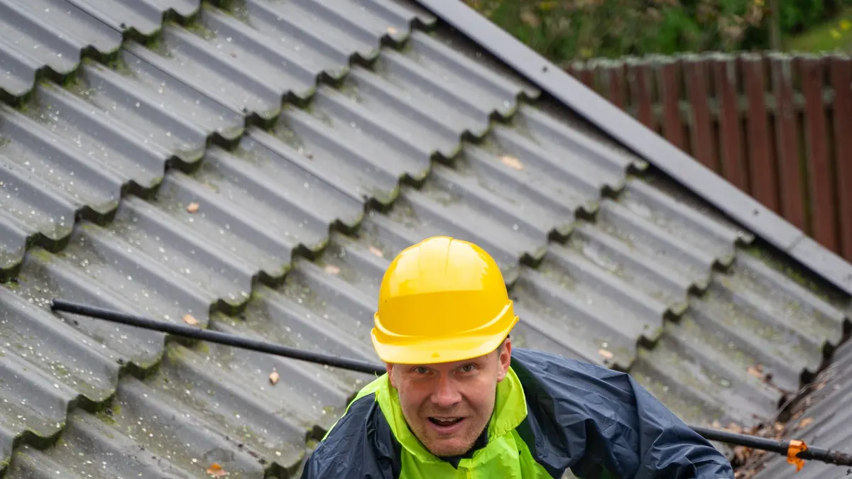 Construction worker wearing safety equipment on a metal roof