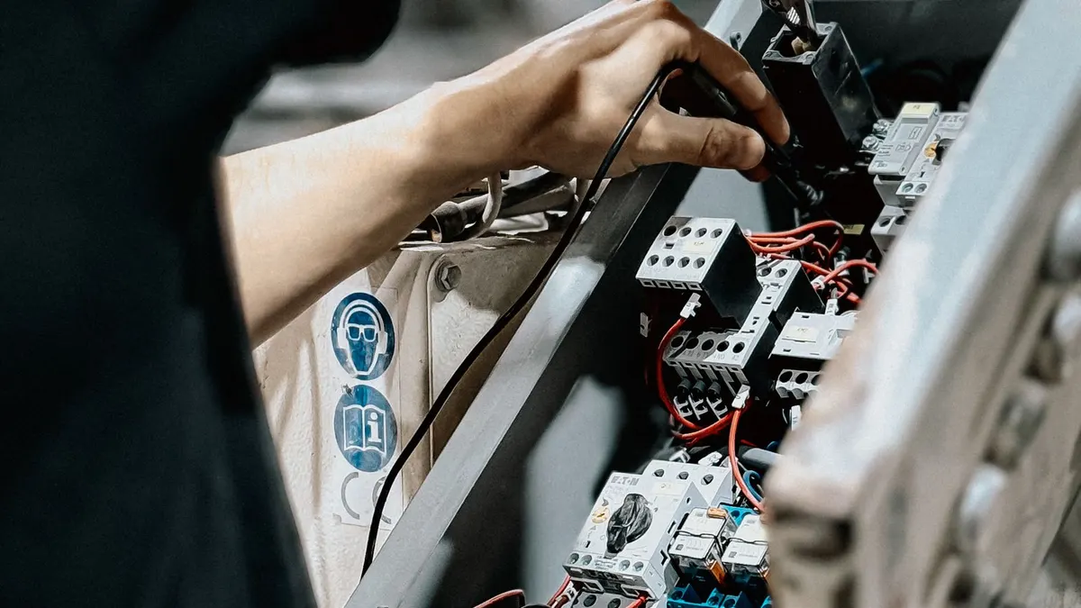 Technician working inside an industrial electrical control panel