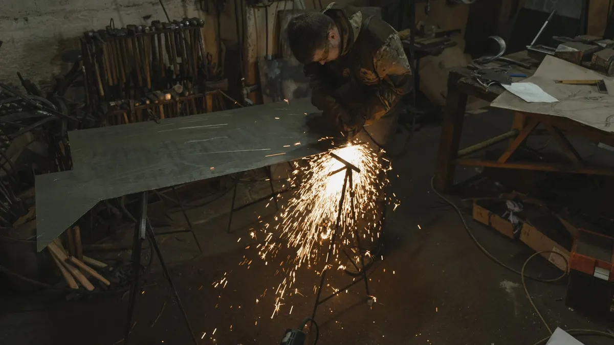 Metalworker cutting a large sheet-metal panel in a fabrication workshop