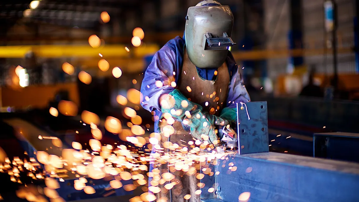 Protected industrial worker fabricating bright metal in a workshop