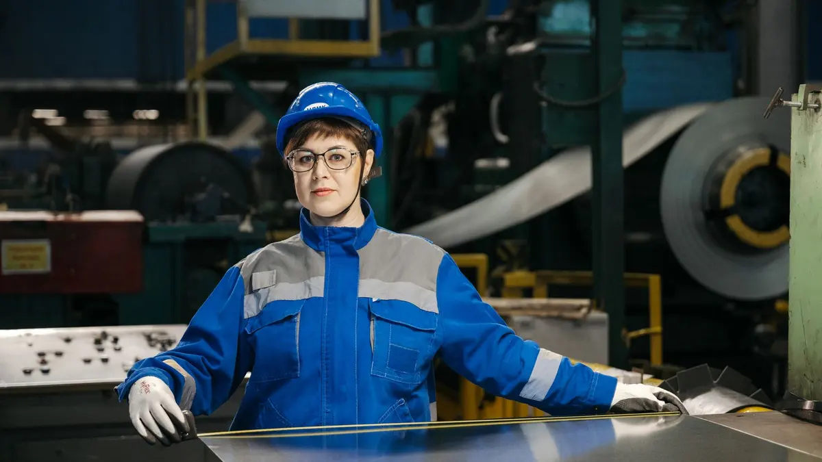 Factory worker handling a large steel sheet in an industrial plant
