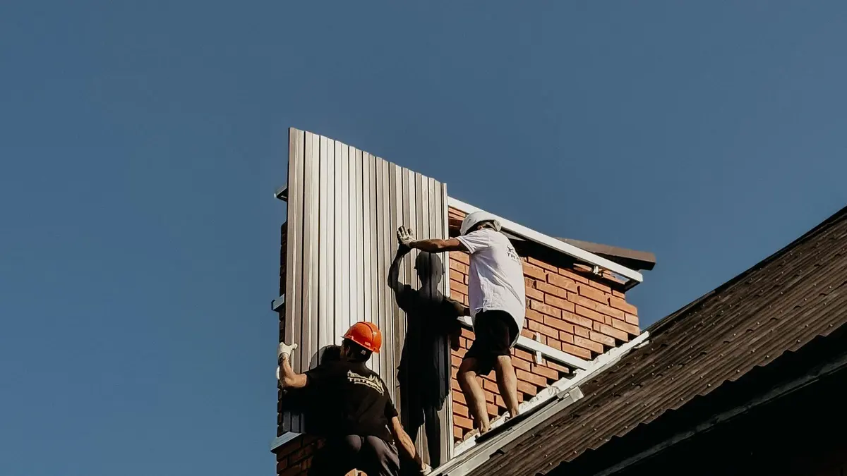 Construction workers installing metal roof panels on a building