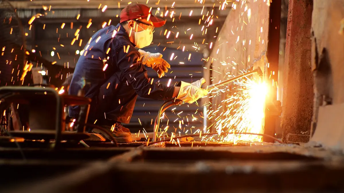 Protected metalworker fabricating steel in an industrial workshop